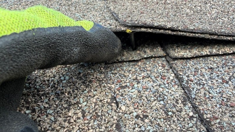 Technician repairing a lifted shingle edge