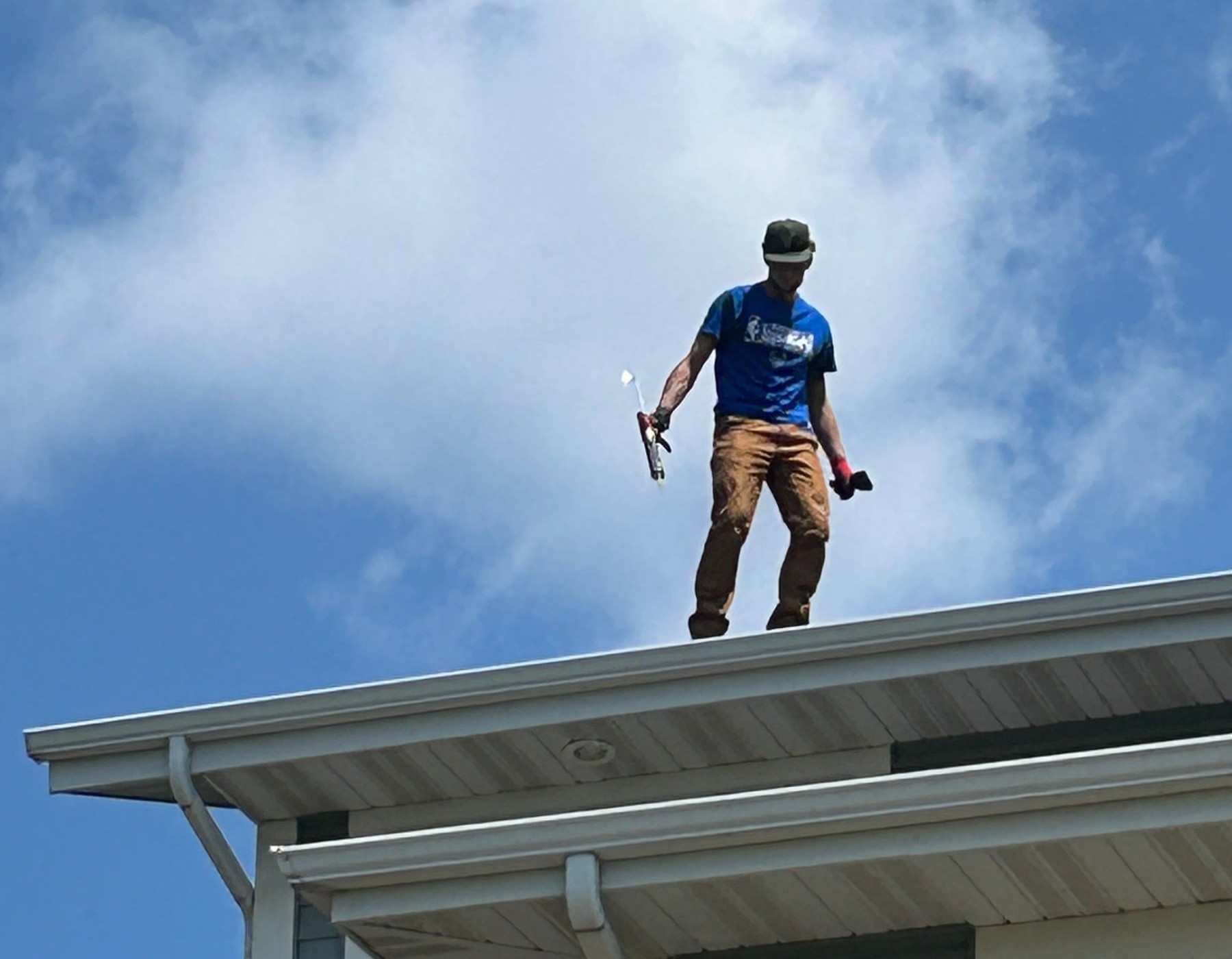 View along a roof ridge overlooking a property, technician's gloved hand in foreground