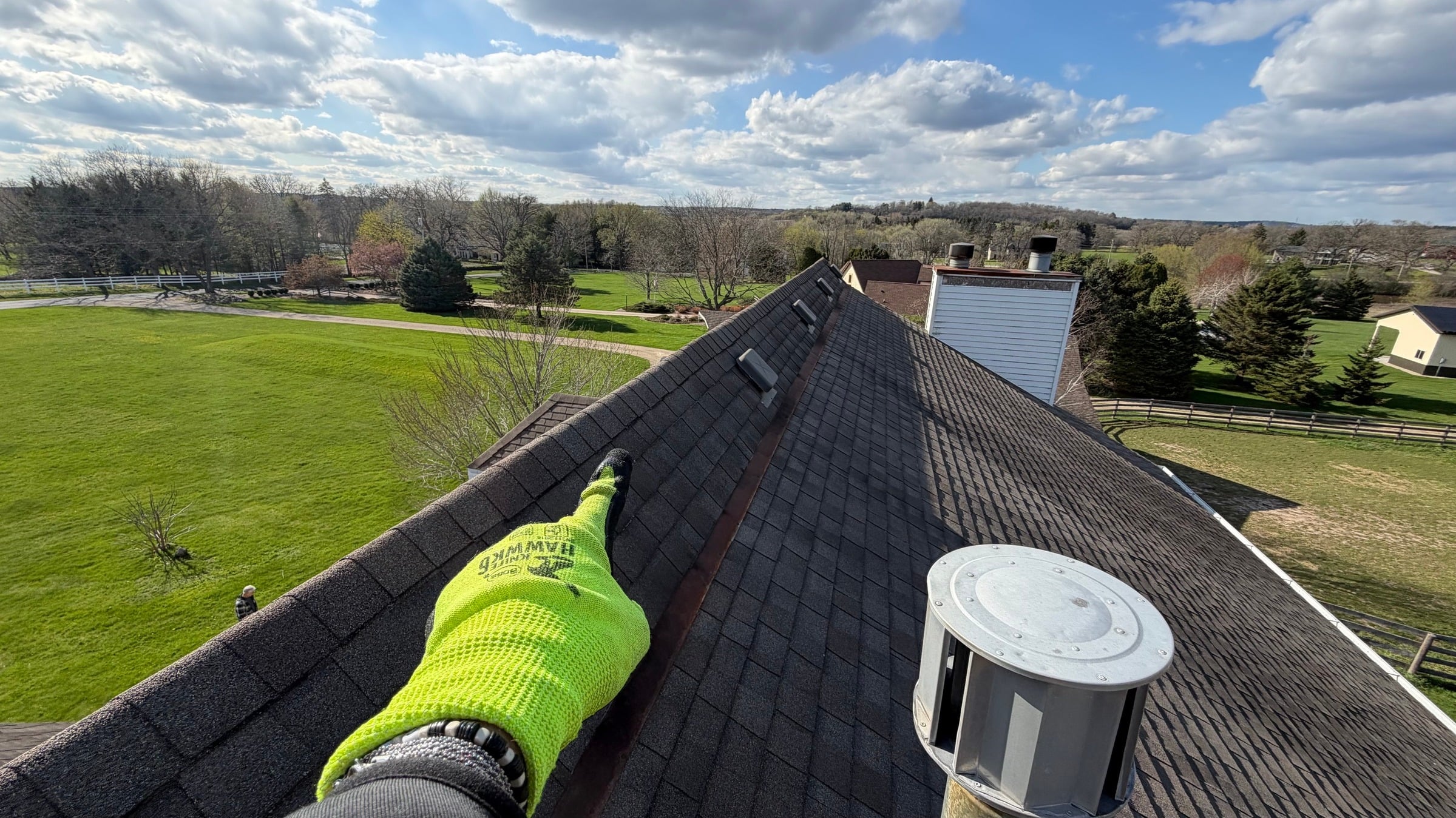 View along a roof ridge overlooking a property, technician's gloved hand in foreground